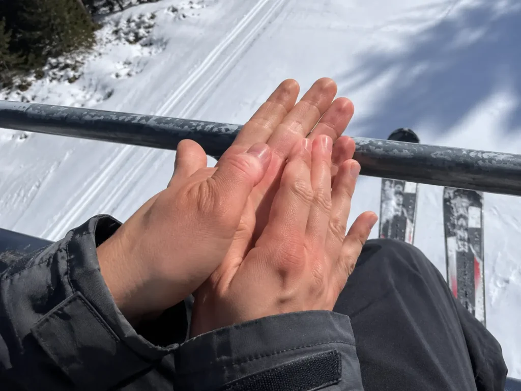 Why do my fingers go numb skiing guide showing bare cold hands on a ski lift