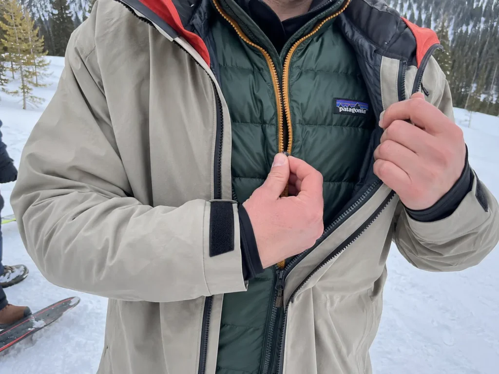 Skiier adding a warm down vest mid layer to fix why do my fingers go numb skiing