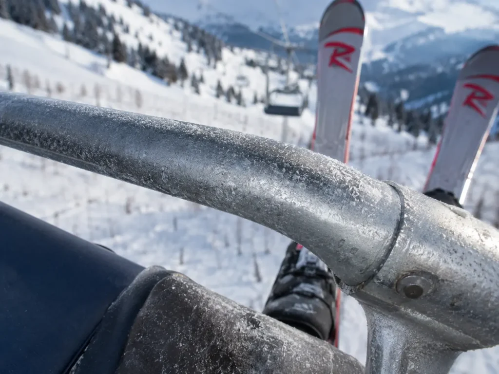 Metal chairlift safety bar showing worn, textured surface