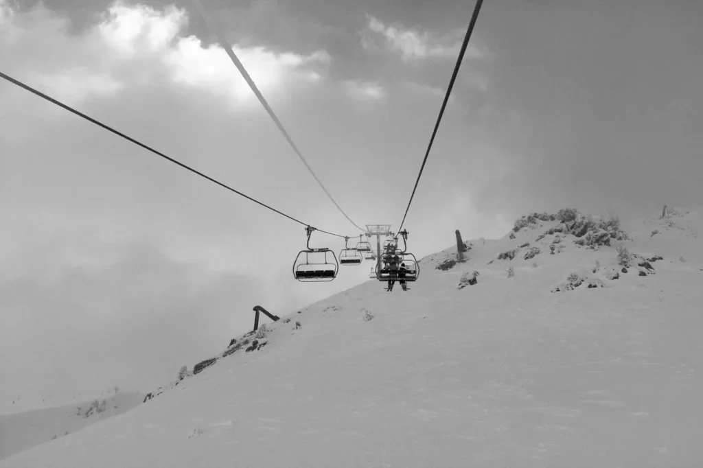 Skier on a chairlift with a high summit view