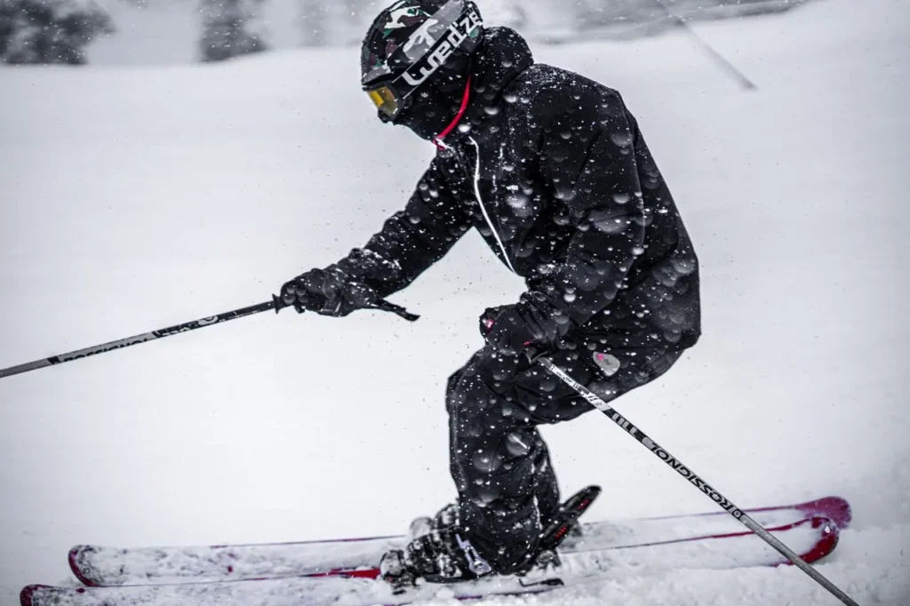 Best ski gloves under $100 — gloved hand gripping a ski pole on a groomed run