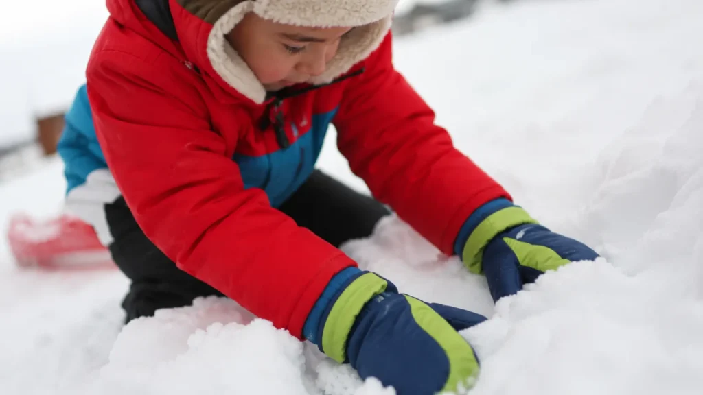 Best ski gloves for kids 2026 — child wearing waterproof gloves while playing in snow