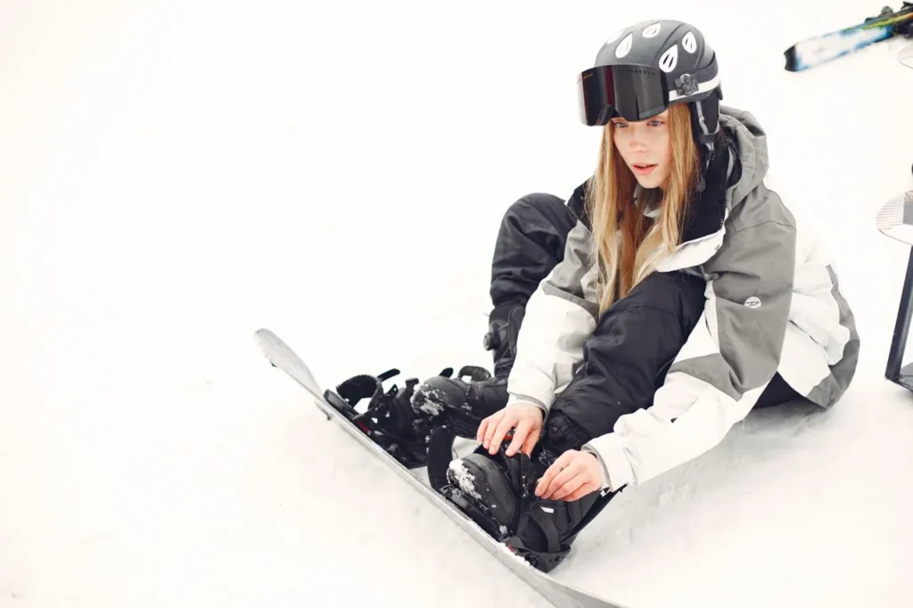 Best ski gloves for women 2026 — gloved hand adjusting a ski binding on the snow