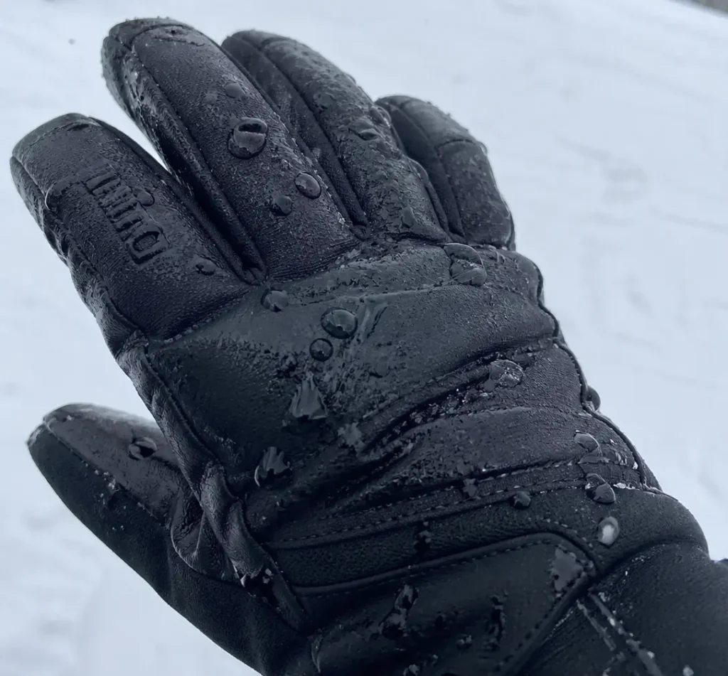 A close-up of water beading off the best waterproof ski gloves in heavy snow