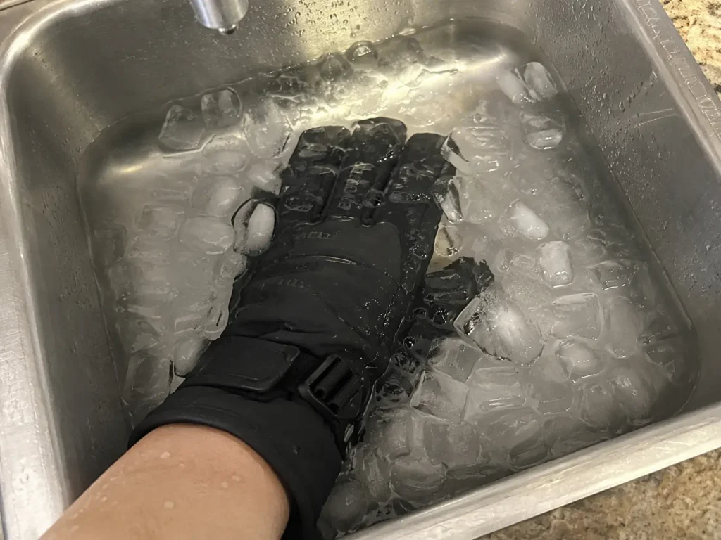 Submerging a budget waterproof ski glove in ice water to check for leaks