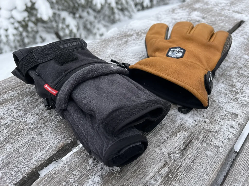 Removable interior liner being pulled from a three finger ski glove to show insulation layers