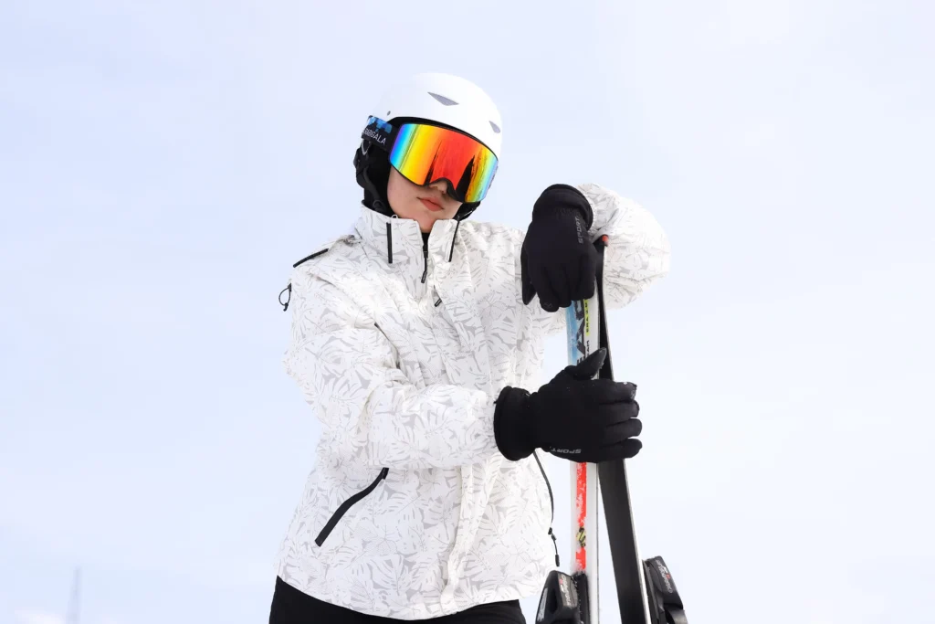 Skier's gloved hand gripping a ski pole on a groomed run