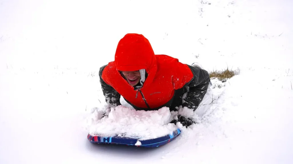 Sledding with gloves on a snowy hill — best gloves for sledding